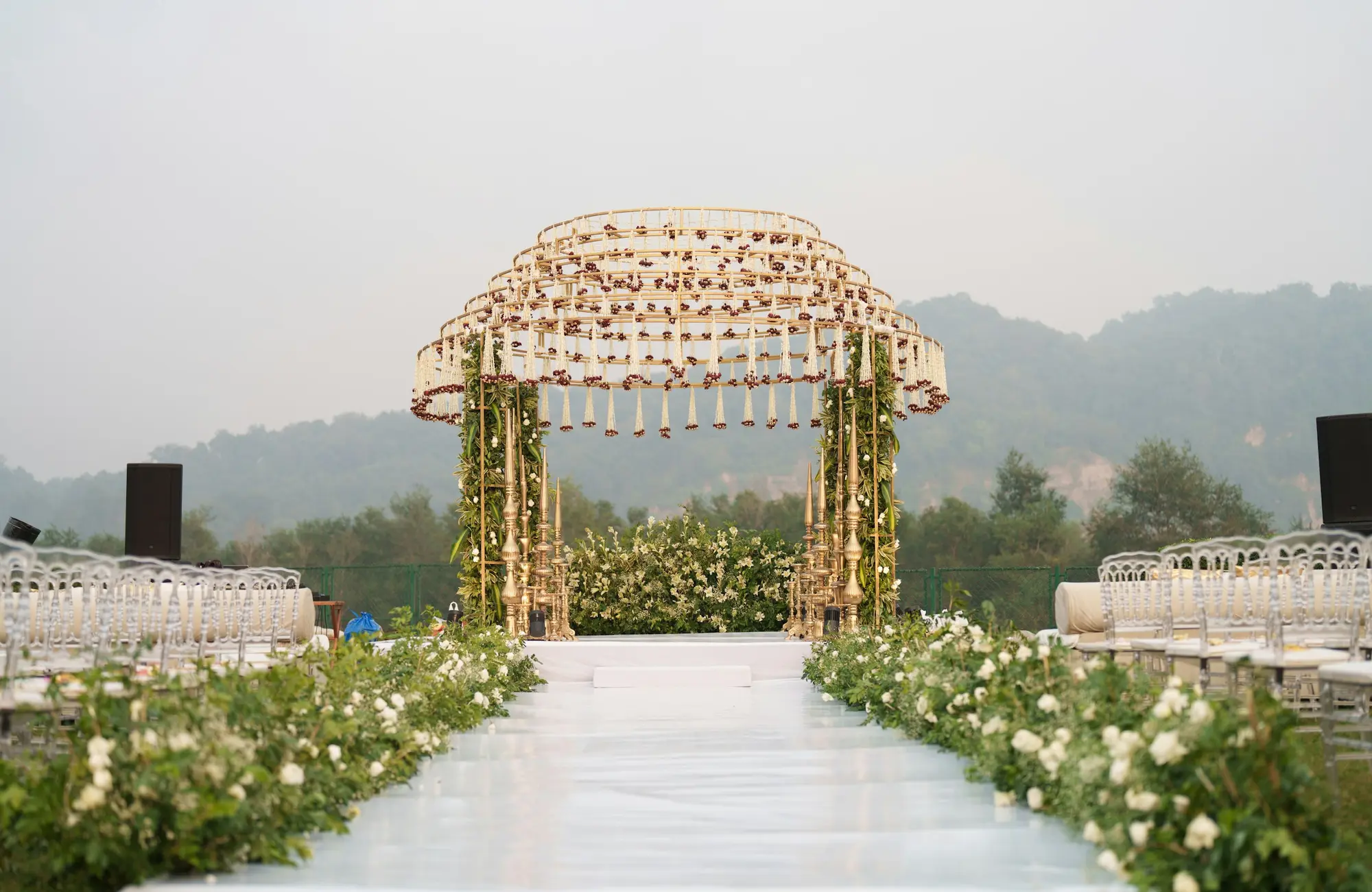 White floral mandap and aisle set in the hills