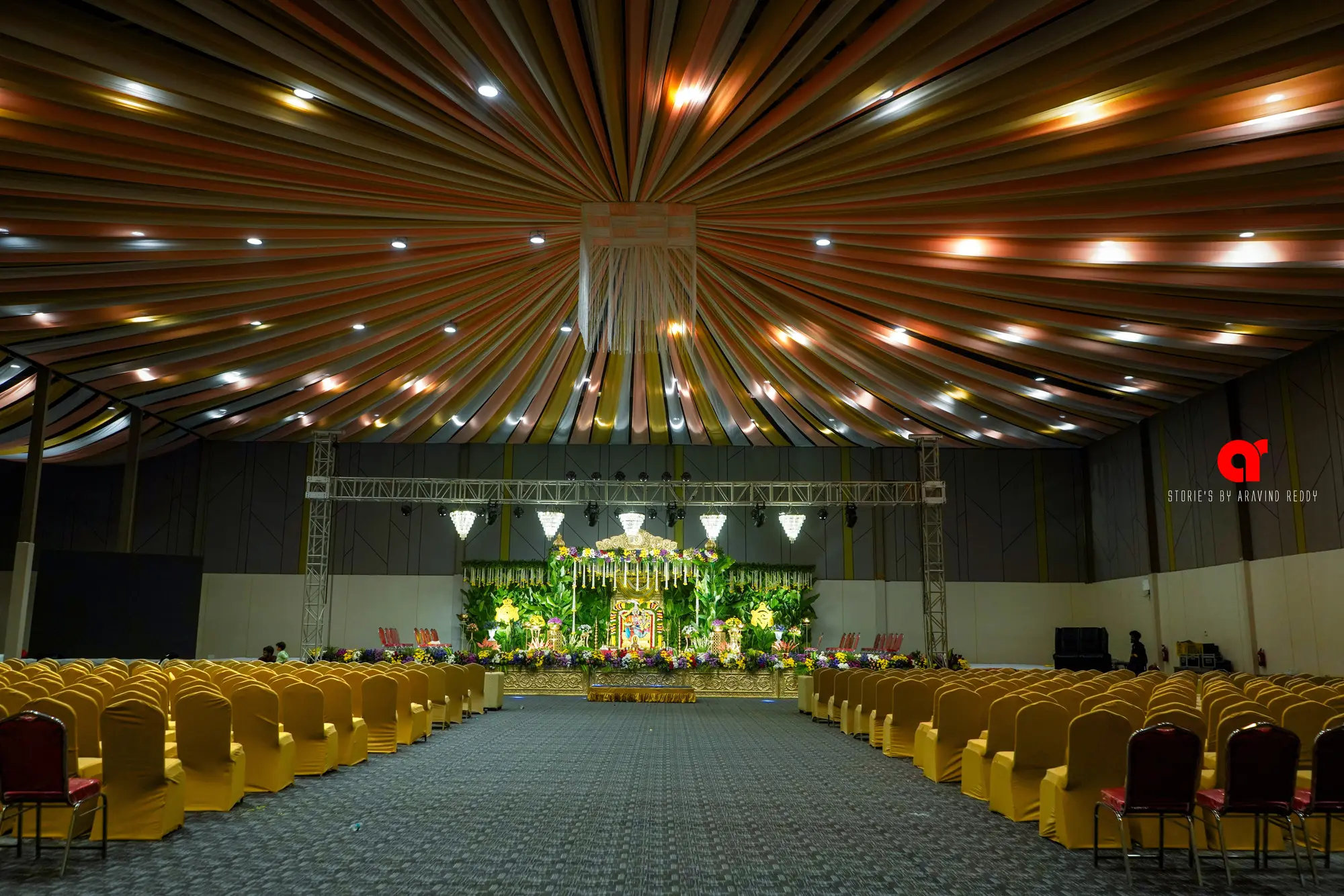 Sri Infinity grand hall dressed for a wedding with a floral stage and gold chairs