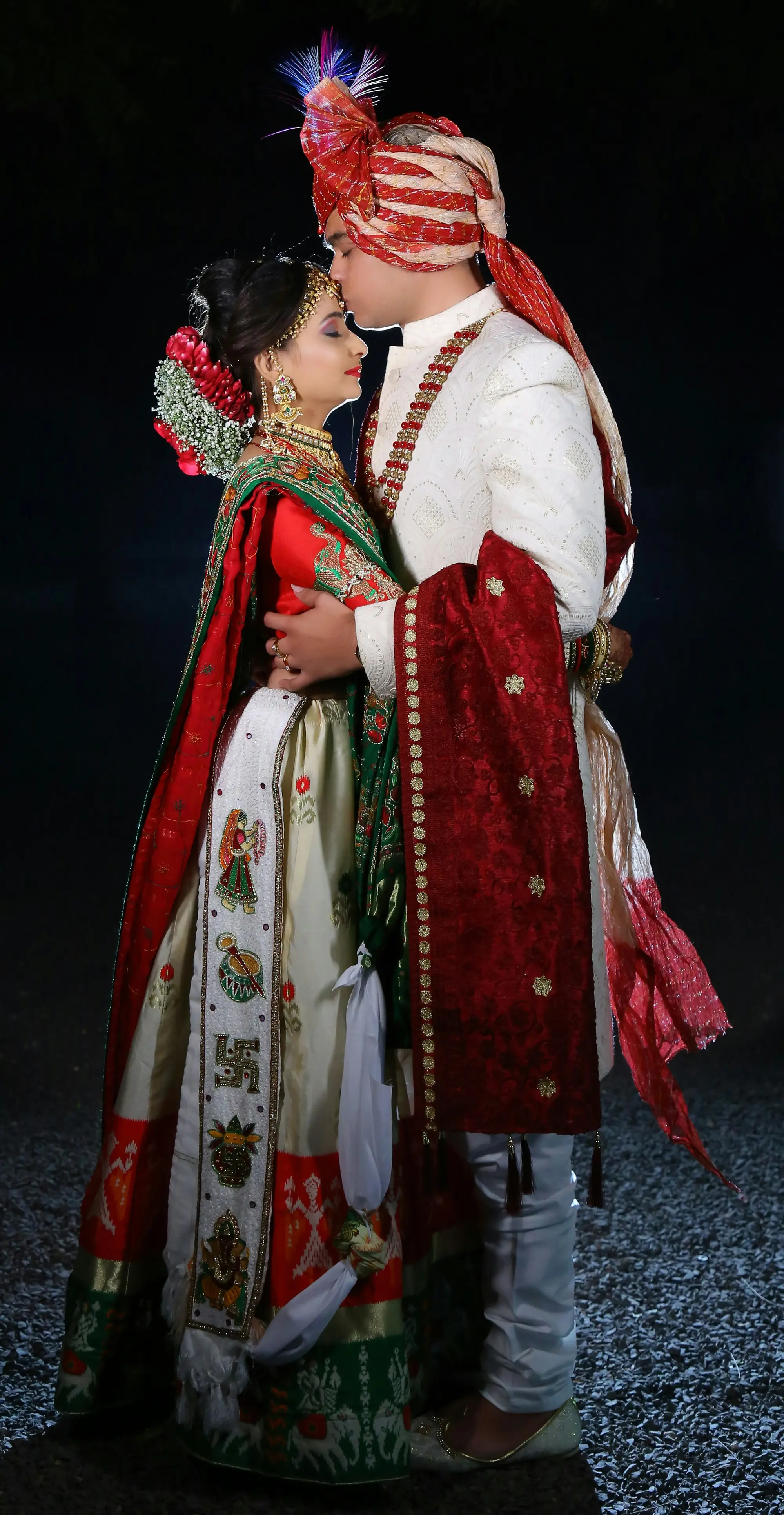 Groom in ivory sherwani embracing bride in red lehenga
